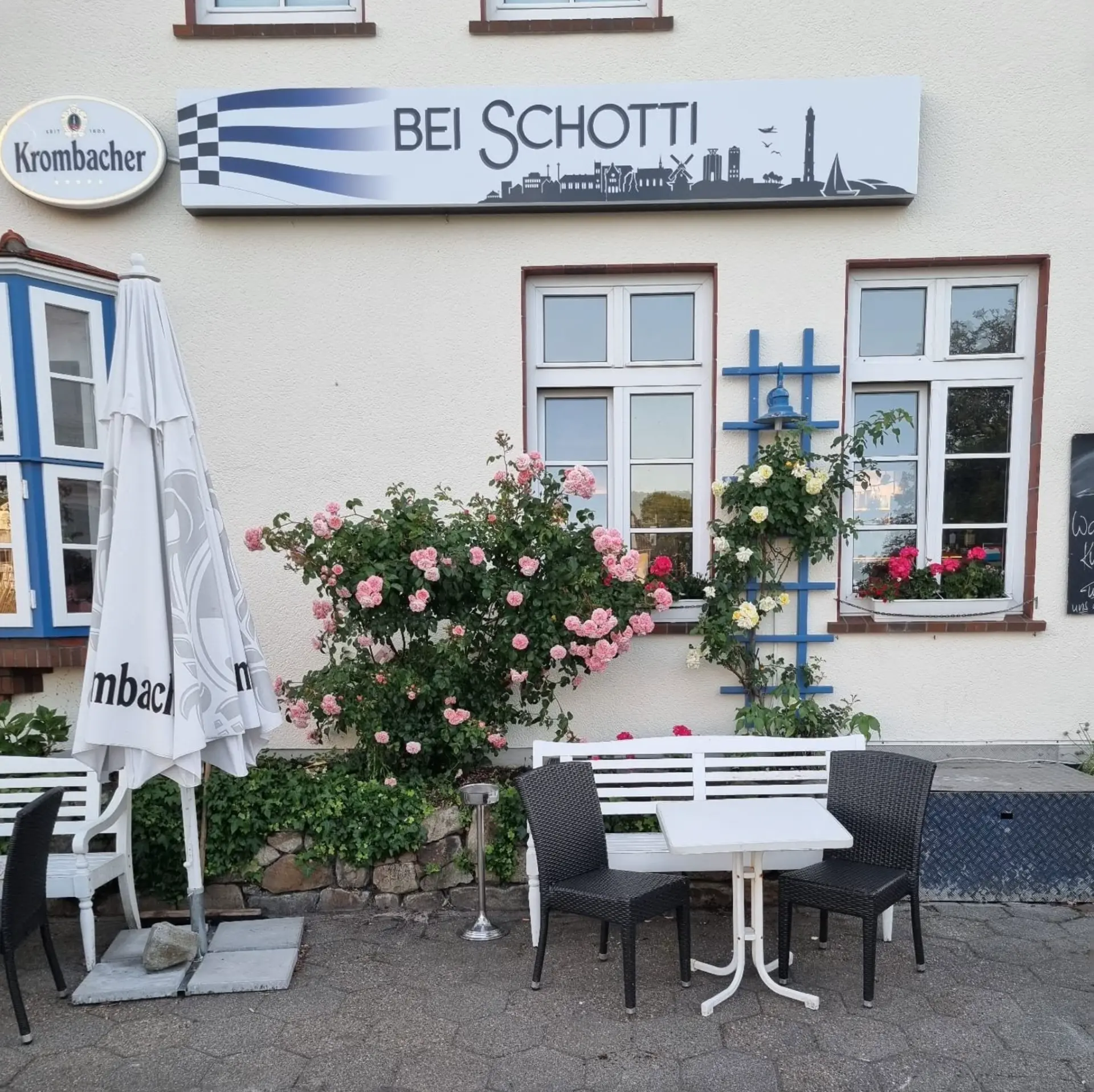 Außenansicht von Bei Schotti auf Norderney mit Terrasse, Rosen und Restaurantschild